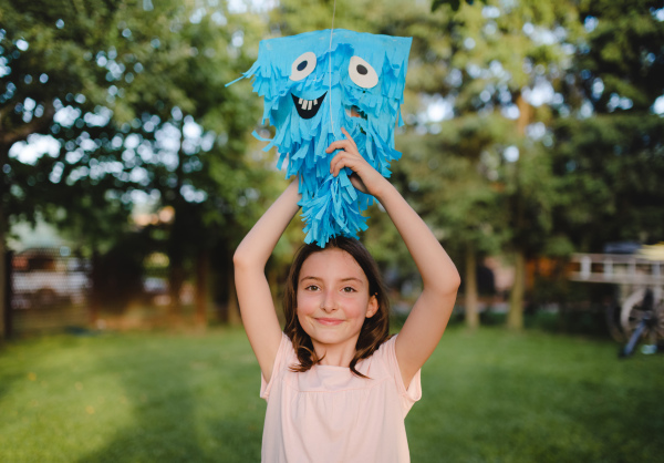 Small girl with kite standing outdoors in garden in summer, a birthday celebration concept.