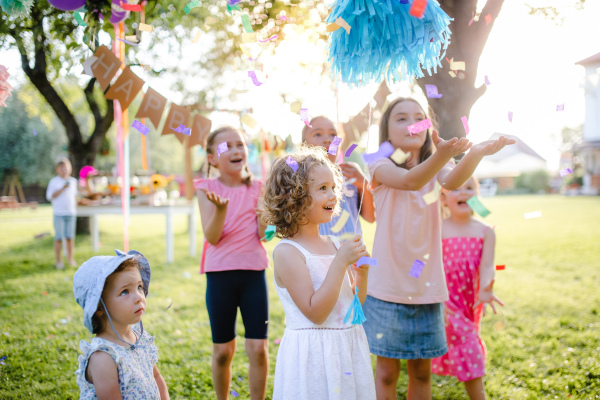 Small children standing outdoors in garden in summer, playing. A celebration concept.