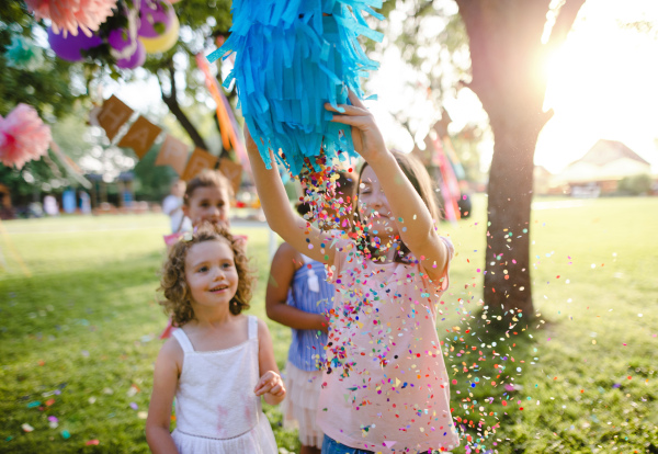 Small children outdoors in garden in summer, playing. A celebration concept.