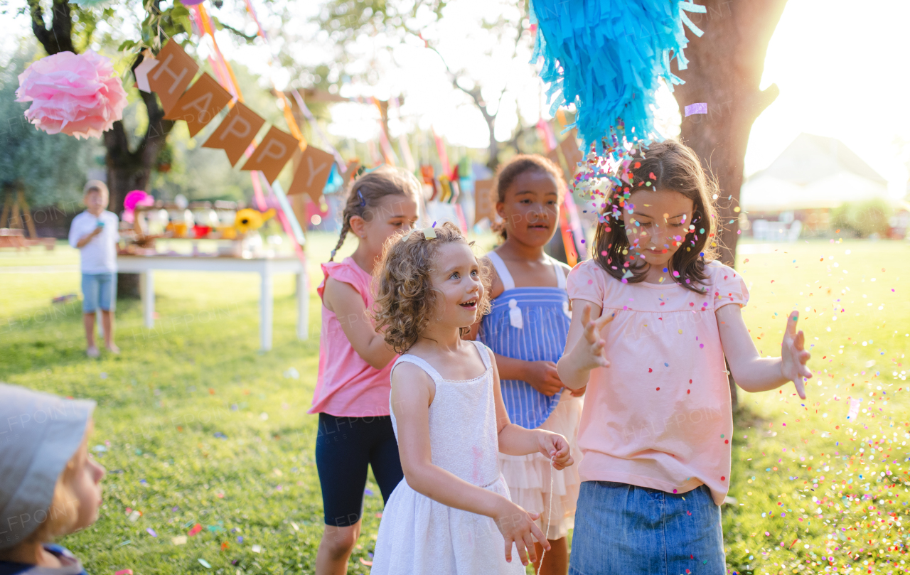 Small children outdoors in garden in summer, playing. A celebration concept.