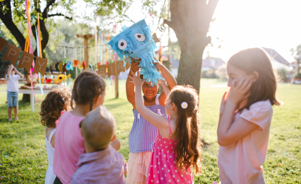 Small children with kite outdoors in garden in summer, playing. A celebration concept.