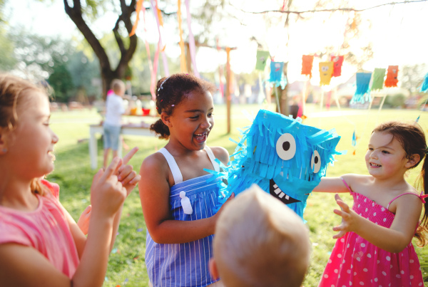 Small children outdoors in garden in summer, playing. A celebration concept.