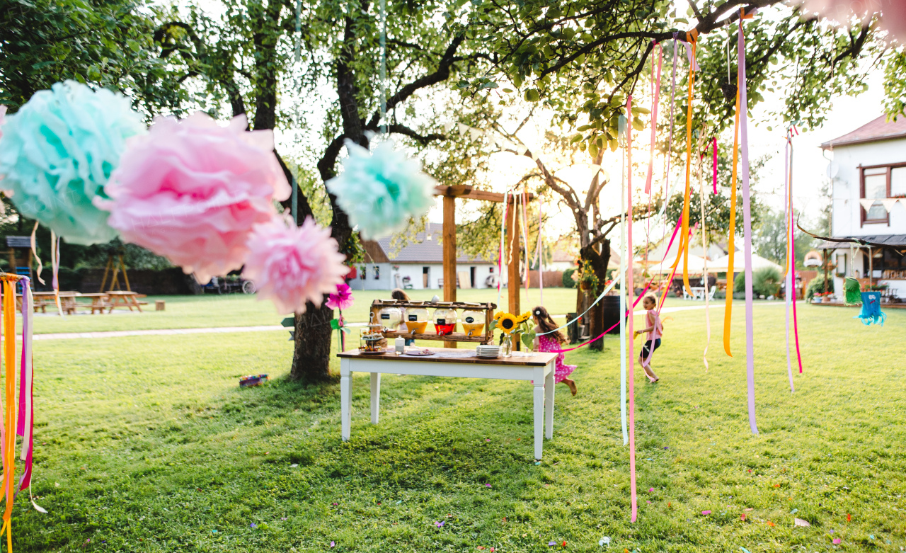 Small children outdoors in garden in summer, playing. A celebration concept.