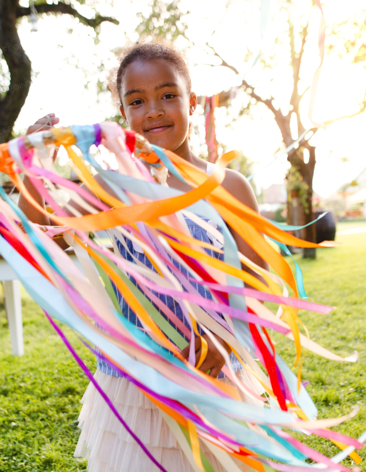 Small girl outdoors in garden in summer, playing with rainbow hand kite. A celebration concept.