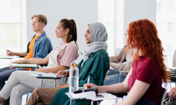 A group of university student sitting in classroom indoors, studying.