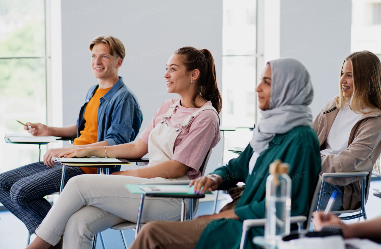 A group of multiethnic university students sitting in classroom indoors, studying.