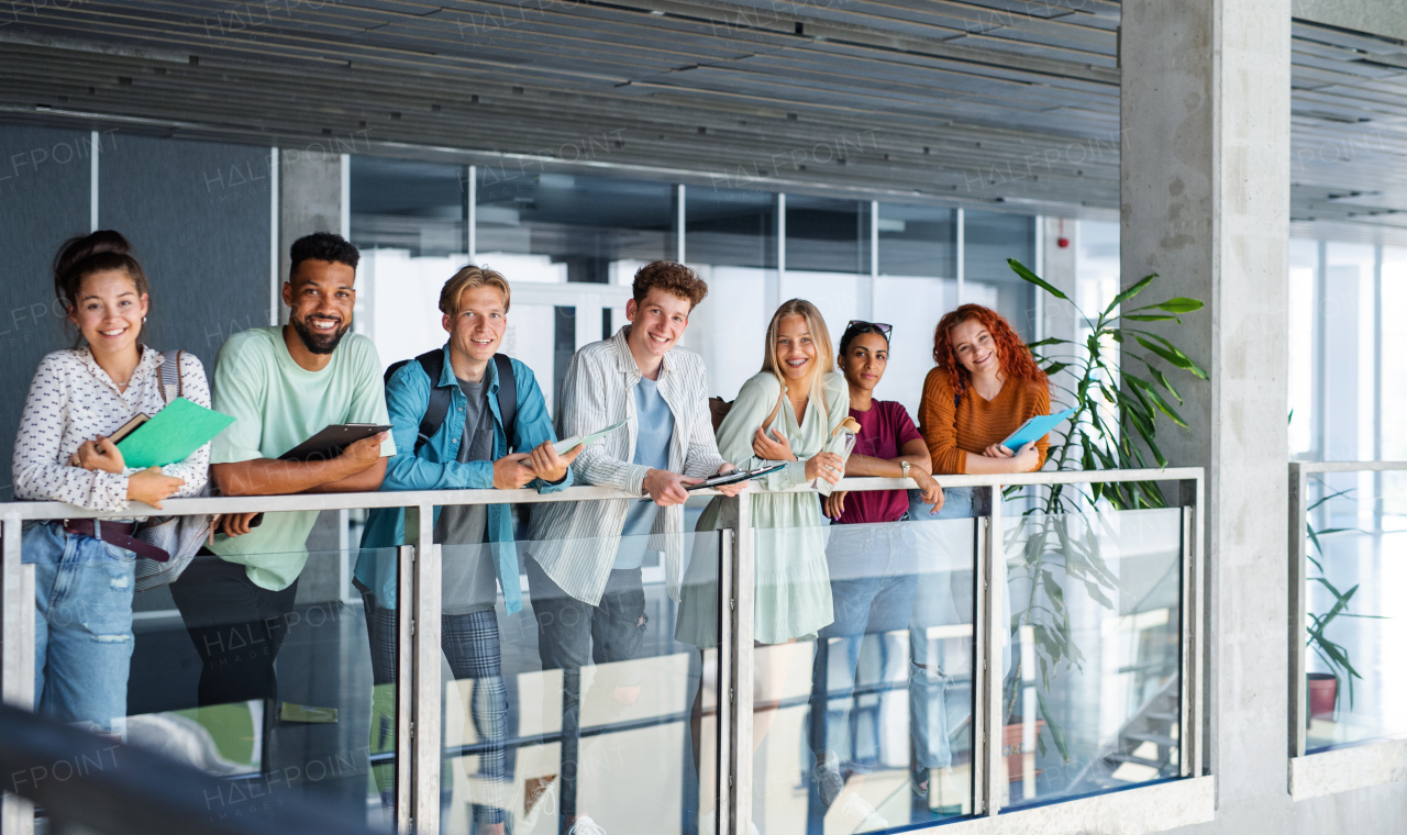 Group of university students standing and looking at camera indoors, back to school concept.