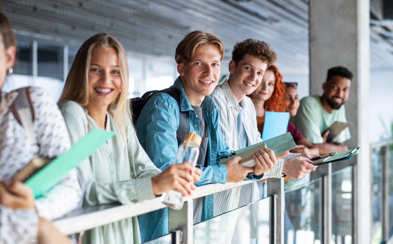 Happy university students standing and looking at camera indoors, back to school concept.