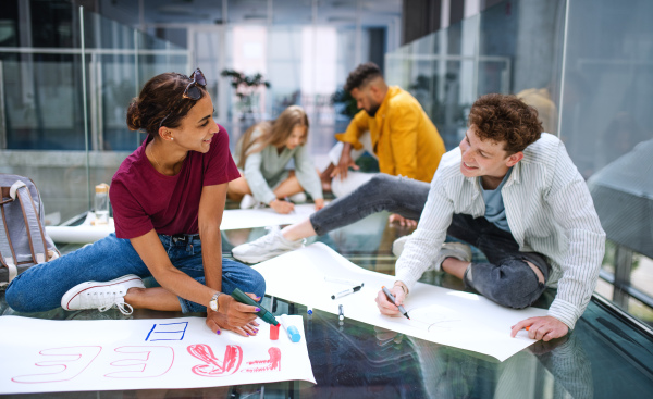 Group of university students activists making banners for protest indoors, fighting for free education concept.