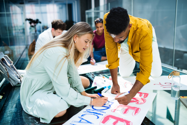 Group of university students activists making banners for protest indoors, fighting for free education concept.