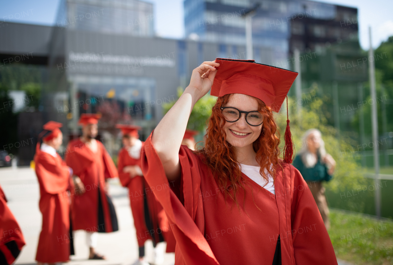 A portrait of cheerful university student celebrating outdoors, graduation concept.