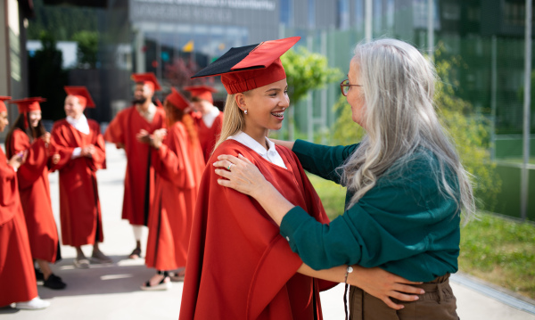 A portrait of cheerful university student with senior professor celebrating outdoors, graduation concept.