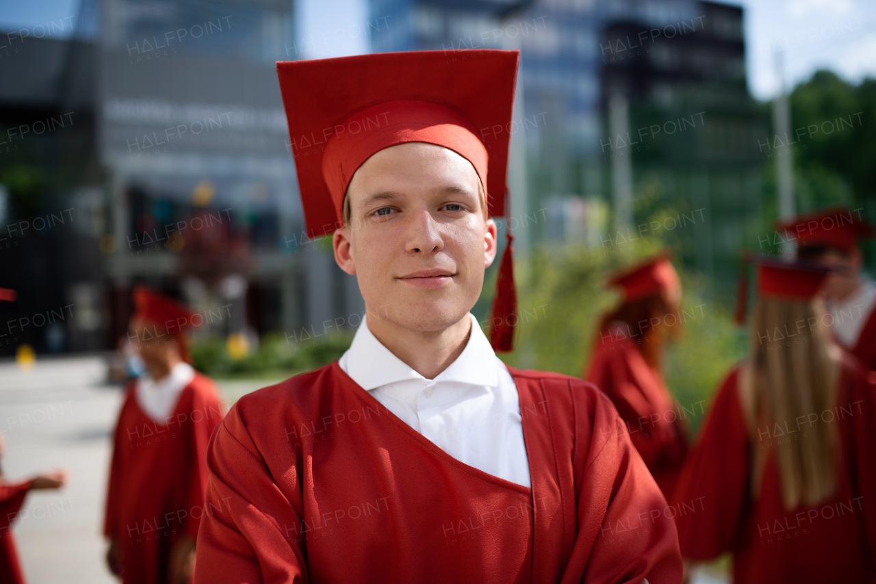 A portrait of cheerful university student celebrating outdoors, graduation concept.