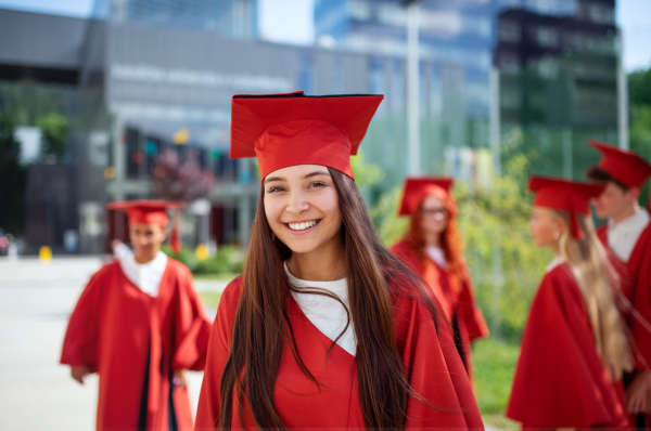 A portrait of cheerful university student celebrating outdoors, graduation concept.