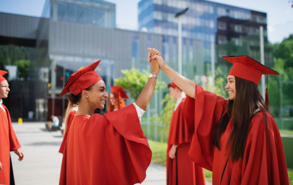 A group of cheerful university students celebrating outdoors, graduation concept.