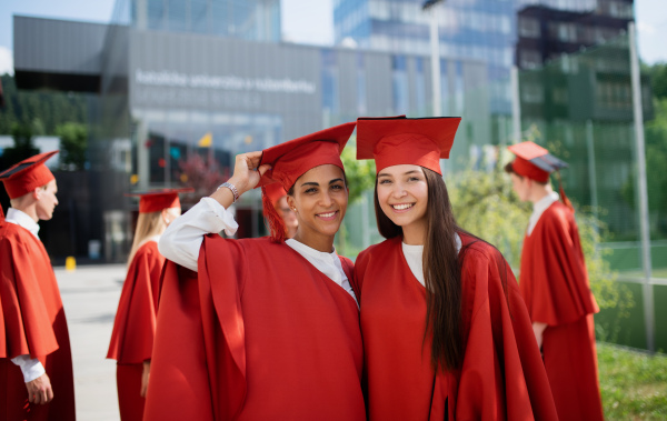 A portrait of cheerful university students celebrating outdoors, graduation concept.