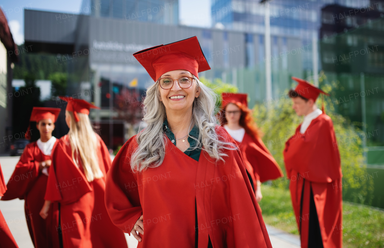 A portrait of cheerful senior woman student outdoors, graduation and third age university concept.