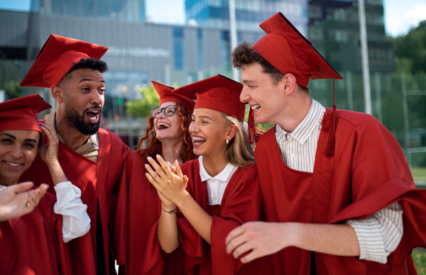 A group of cheerful university students celebrating outdoors, graduation concept.