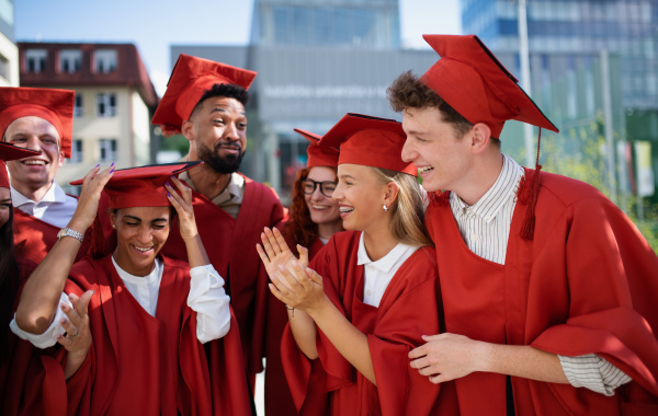 A group of cheerful university students celebrating outdoors, graduation concept.