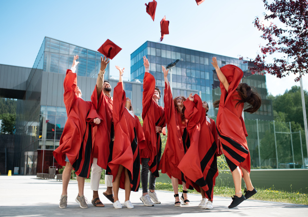 A group of cheerful university students celebrating outdoors, graduation concept.