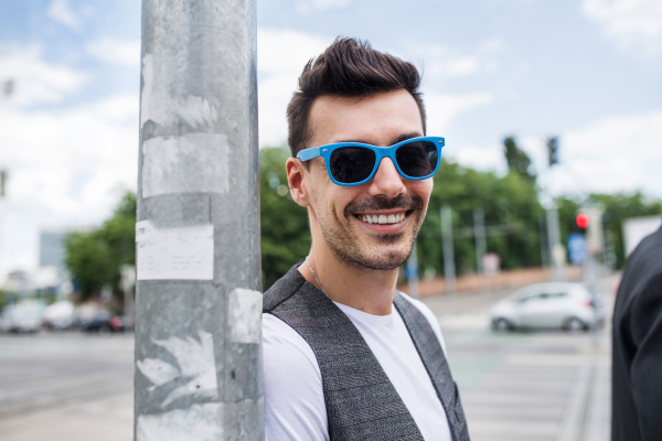 Front view portrait of young blind man standing in city.