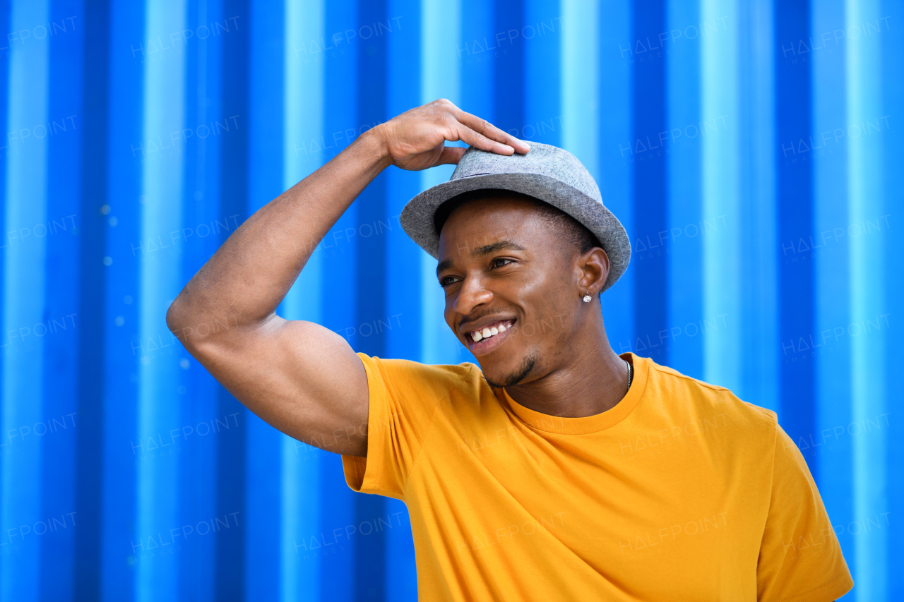 Portrait of cheerful young black man standing against blue background, black lives matter concept.