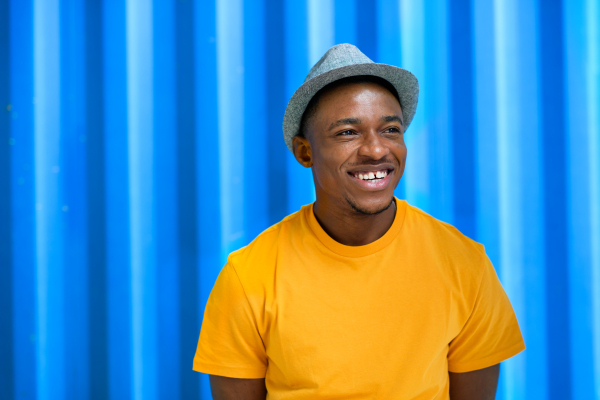 Portrait of cheerful young black man standing against blue background, black lives matter concept.