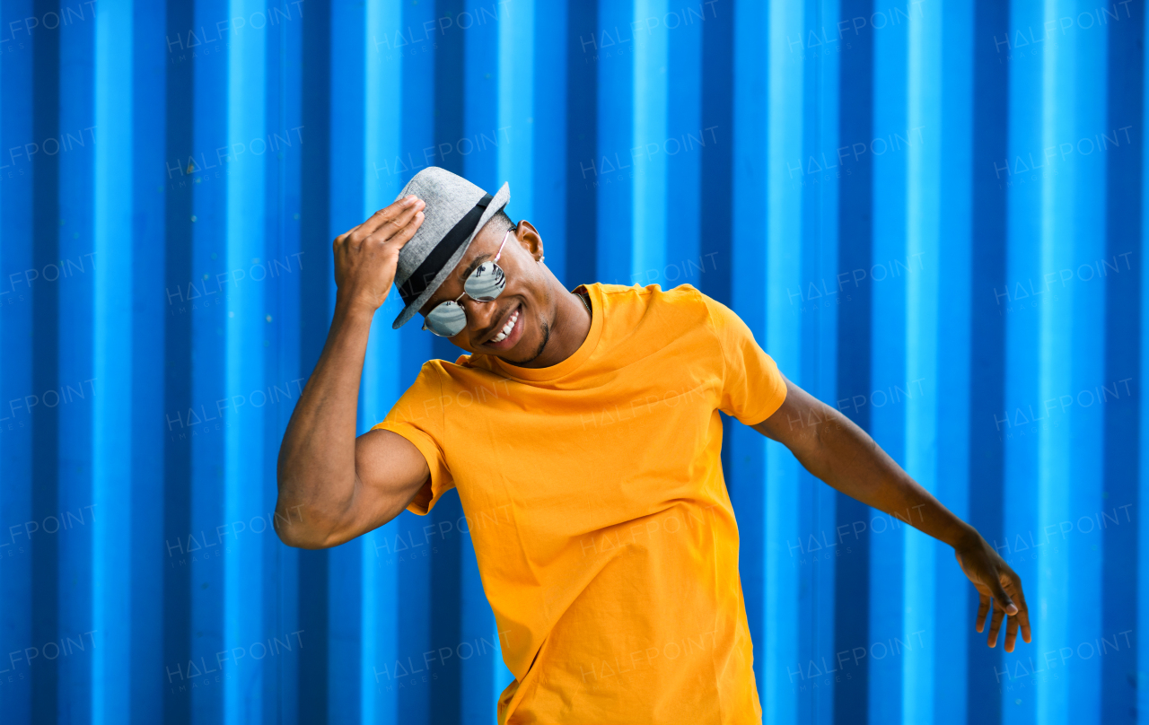 Portrait of cheerful young black man standing against blue background, black lives matter concept.