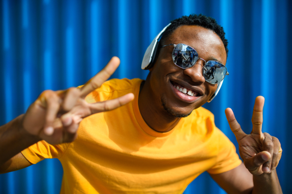 Cheerful young black man standing against blue background, peace gesture and black lives matter concept.