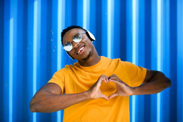 Portrait of cheerful young black man standing against blue background, black lives matter concept.