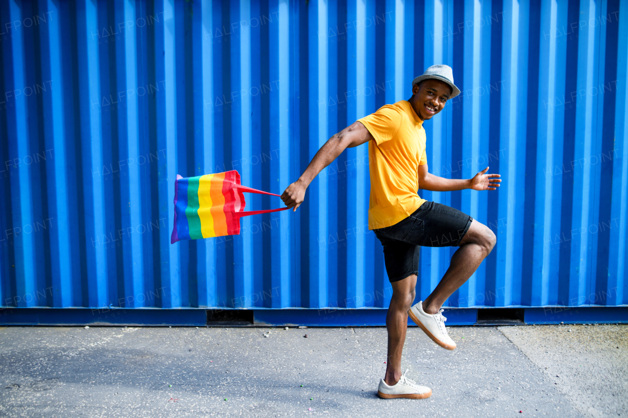 Side view of young black man with rainbow bag walking, black lives matter concept.