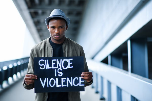 Young man with silence is violence sign standing outdoors in city, black lives matter concept.