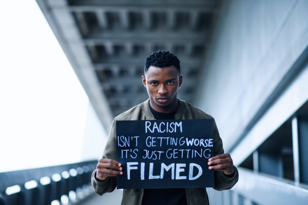 Portrait of man with written sign standing outdoors, black lives matter concept.