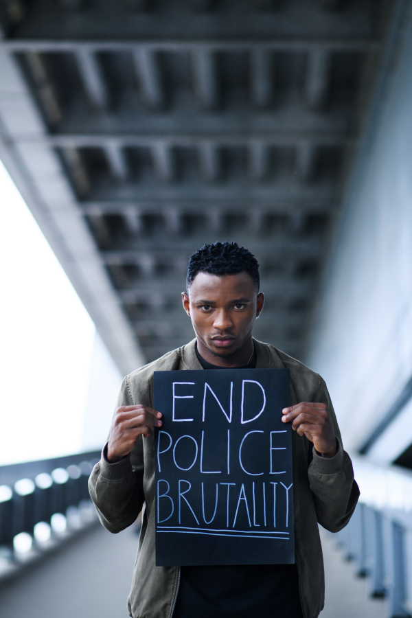 Man with end police brutality sign standing outdoors, black lives matter concept.