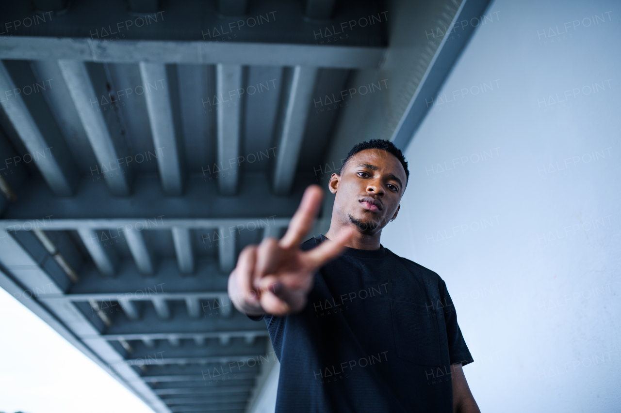 Portrait of black man with peace gesture outdoors in city, black lives matter concept.