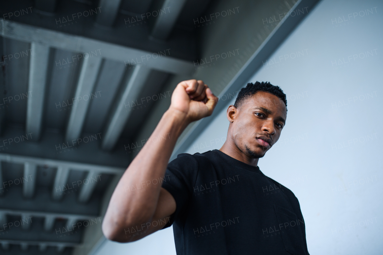 Portrait of black man with raised fist standing outdoors in city, black lives matter concept.