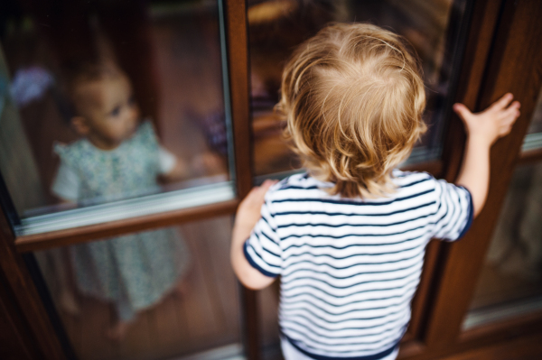 Two toddler children playing outdoors on a terrace in summer.