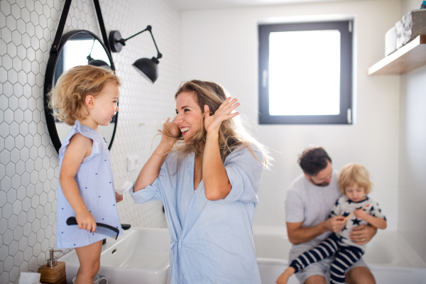 A young family with two small children indoors in bathroom, having fun.