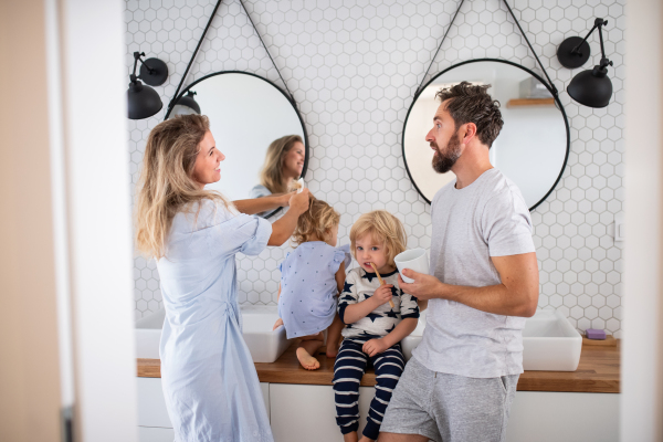 A young family with two small children indoors in bathroom, talking.