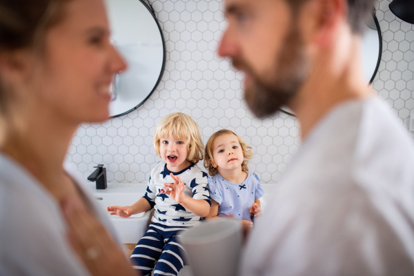 A young family with two small children indoors in bathroom, talking.