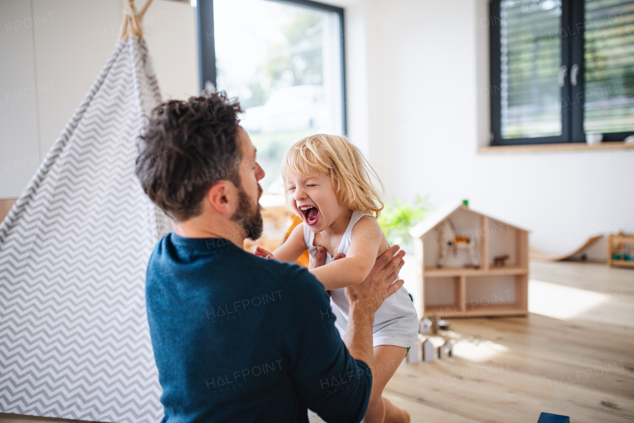 A young family with small child indoors in bedroom having fun.