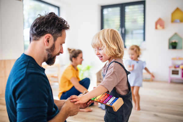 Young family with two small children indoors in bedroom, playing.