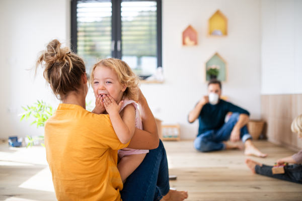 Young family with two small children indoors in bedroom, having fun.