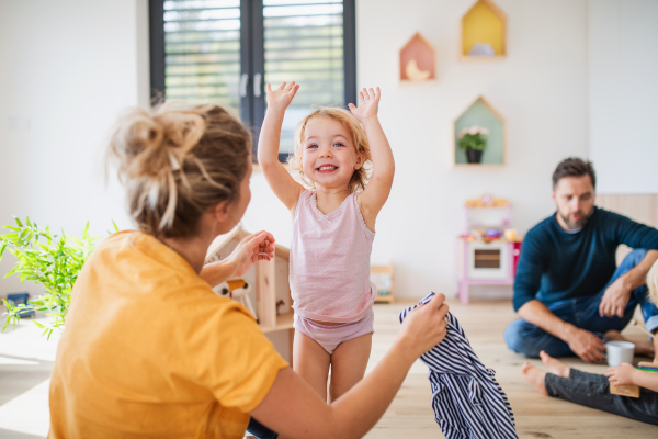 Young family with two small children indoors in bedroom, having fun.