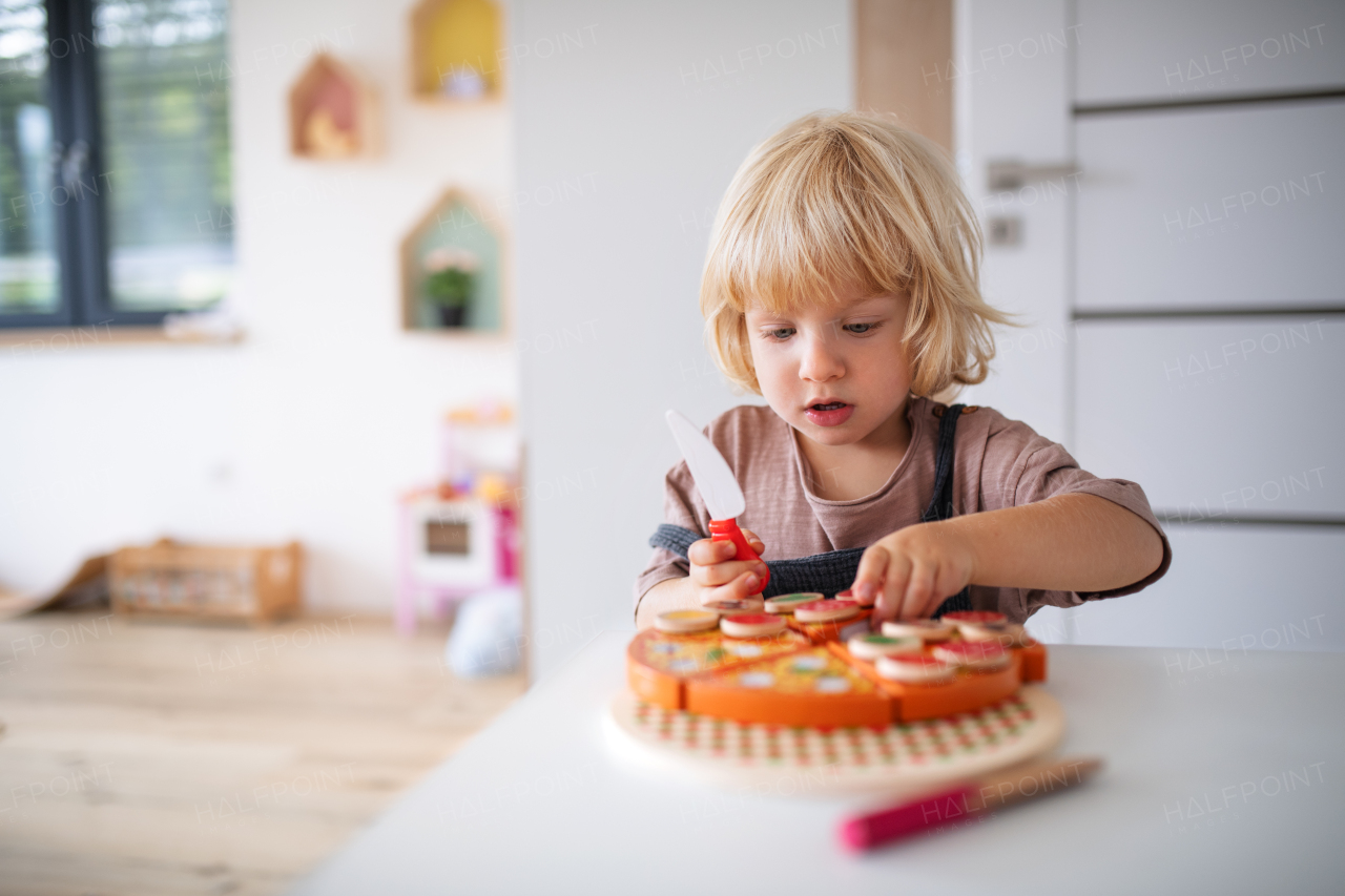 A cute small toddler boy indoors in bedroom playing.