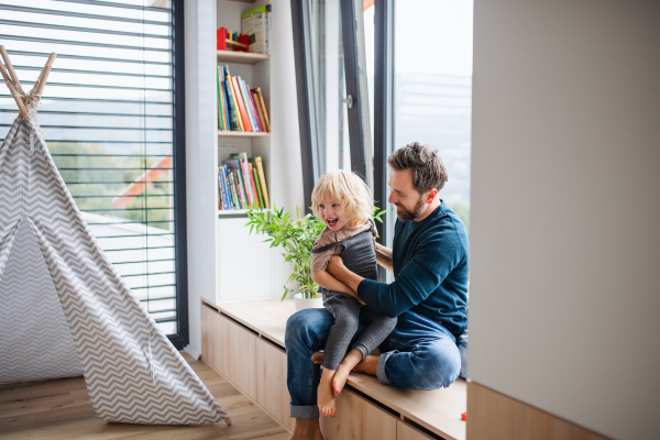 Mature father with small boy playing indoors in bedroom, playing.