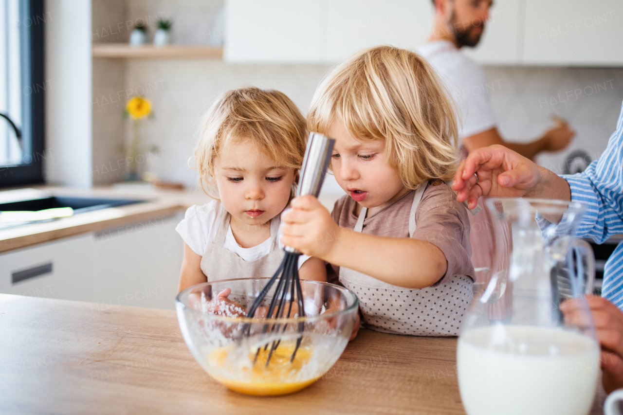 A midsection of young family with two small children indoors in kitchen, preparing food.