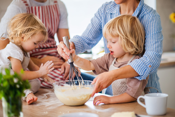 A midsection of young family with two small children indoors in kitchen, cooking.