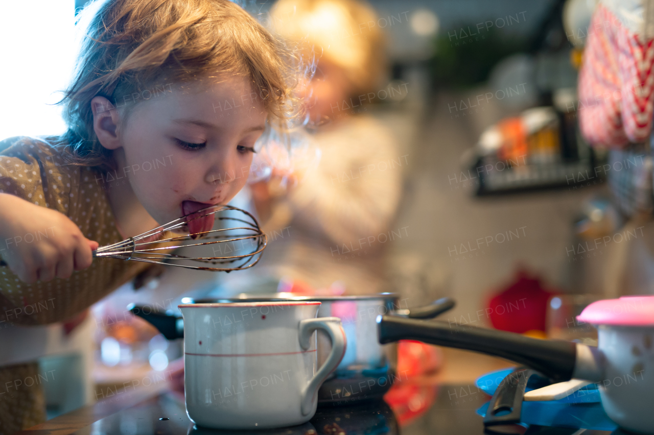 Happy small boy and girl indoors in kitchen at home, helping with cooking.