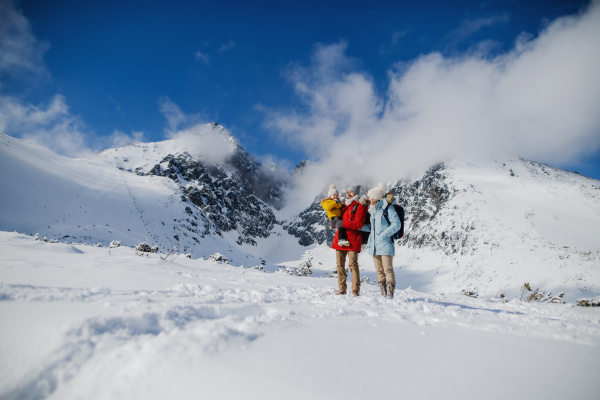 Front view portrait of father and mother with small son in winter nature, standing in the snow.